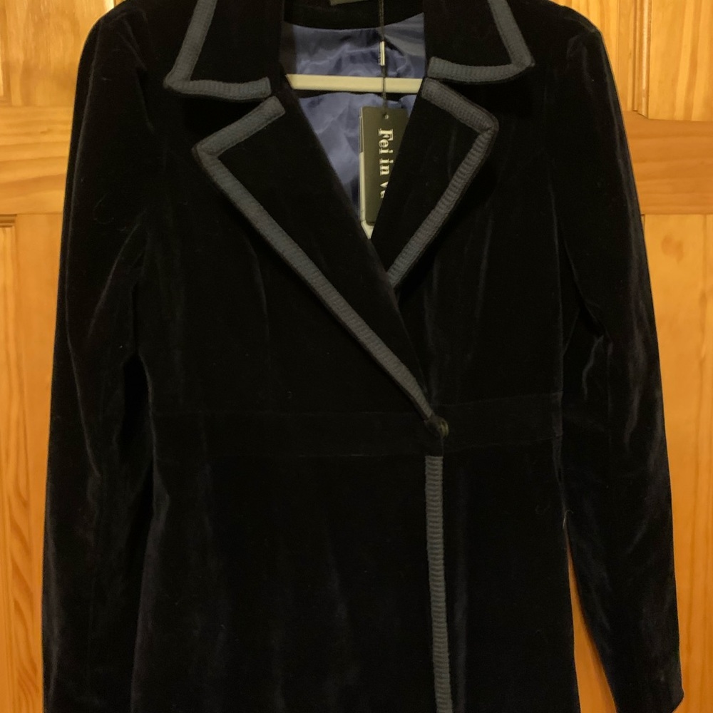 Long, flared velvet navy coat with contrasting light blue trim.